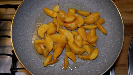 potatoe quarters are being fryed in hot pan with hot and boiling oil on gas stove