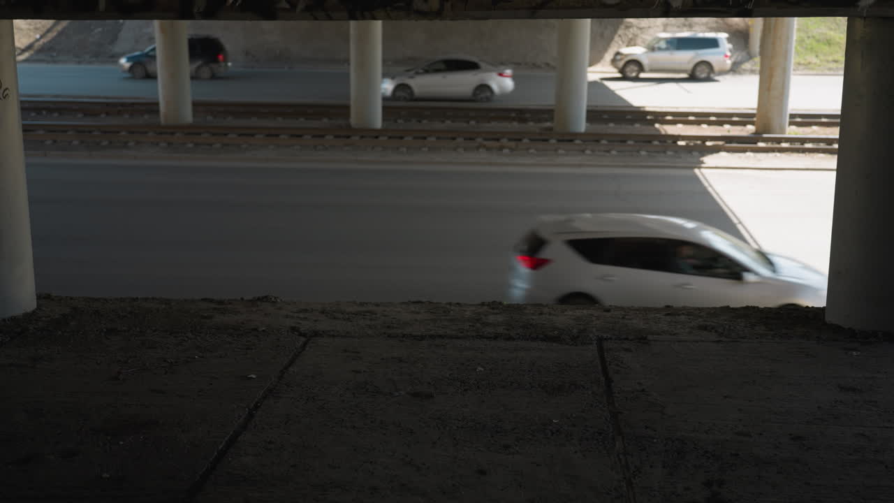 도시 도로에서 다리 아래로 운전하는 자동차의 가까운 시각, 그것은 지나가는 차량의 모션 흐릿함을 포착합니다