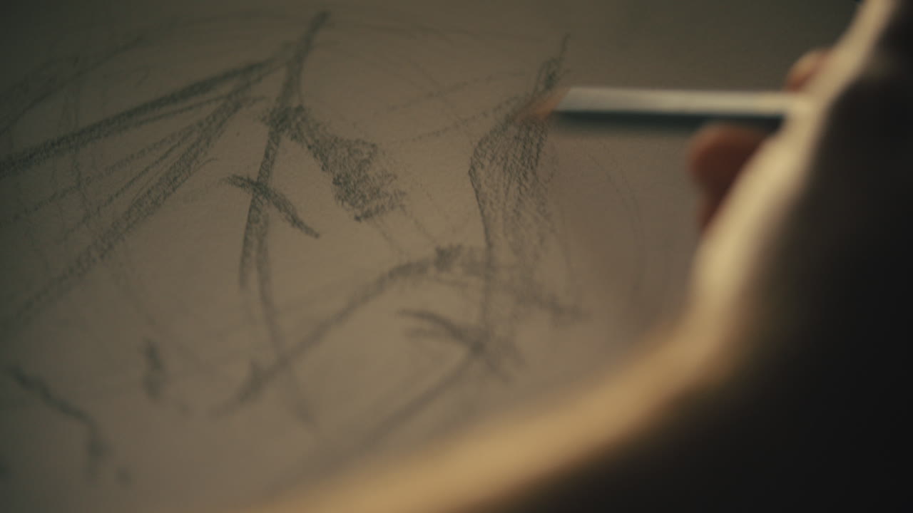 태양이 창에서 패드를 비추는 동안 예술가는 스케치 패드에 얼굴을 그립니다.