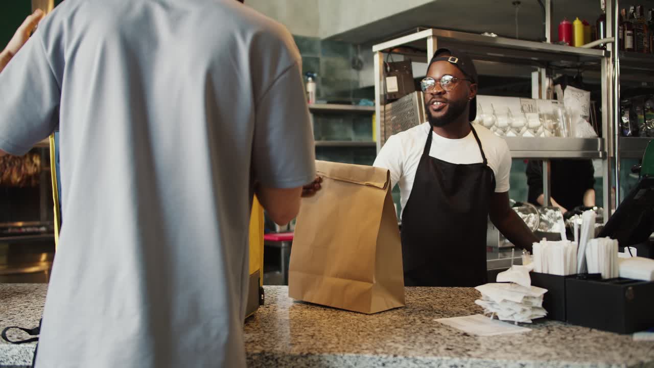 un hombre con gafas da un pedido a un repartidor de alimentos en un mercado de donantes, y intercambian tokens de aprobación. el camino de la comida a su mesa