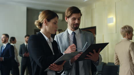 caucasian businesswoman and her male colleague talking and discussing documents in the hall at a meeting