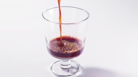 pouring black and hot coffee into a clear cup of coffee close up shot