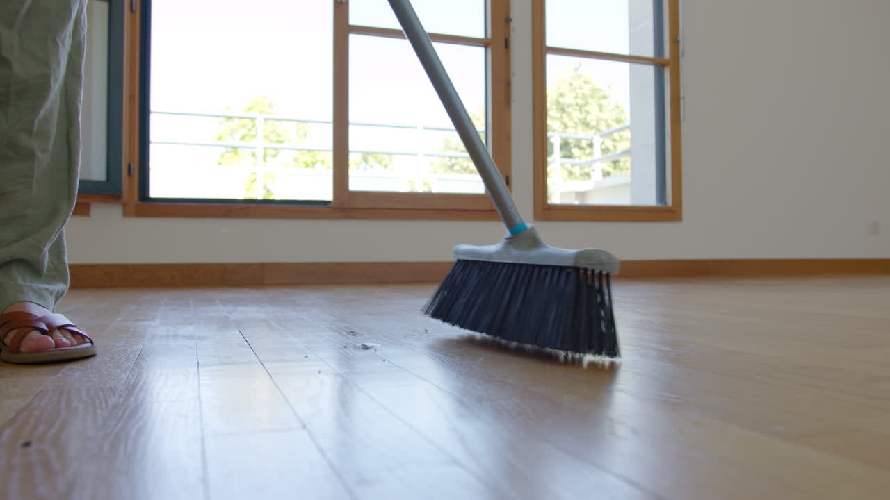 Person Sweeping Over Wooden Floor Of A House. Close-up Shot