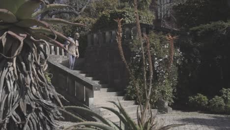 traveler with backpack walking down the stairs in public park, summer, oporto, spain, static shot