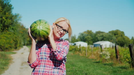 woman carrying a watermelon on a farm