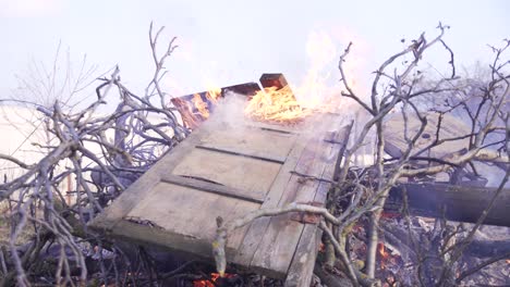 a pile of branches and wooden debris burning