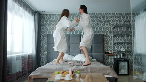 couple jumping on bed in hotel room