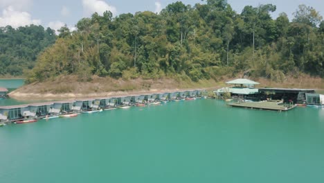 imágenes épicas de drones que revelan a un grupo de personas nadando por bungalows sobre el agua en el parque nacional de khao sok tailandia