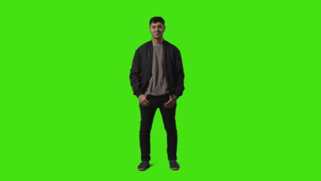 Full-Length-Shot-Of-Smiling-Casually-Dressed-Young-Man-Standing-Against-Green-Screen-With-Hands-In-Pockets