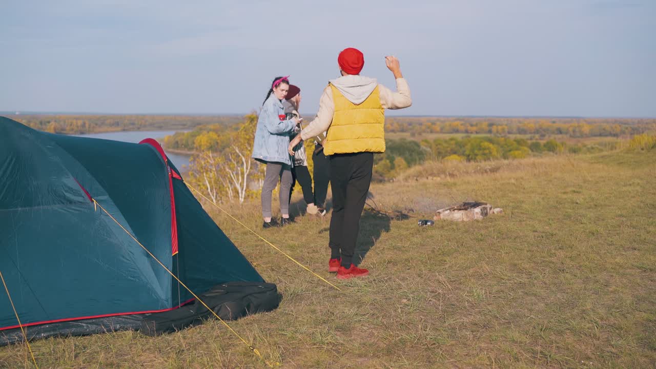 el tipo sale de la tienda estira los brazos y las chicas hablan en el campamento