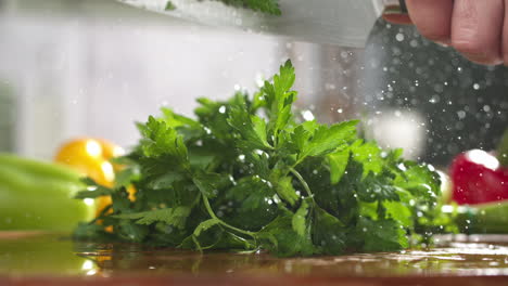 slow motion of parsley chopped with a knife on wooden board in a kitchen