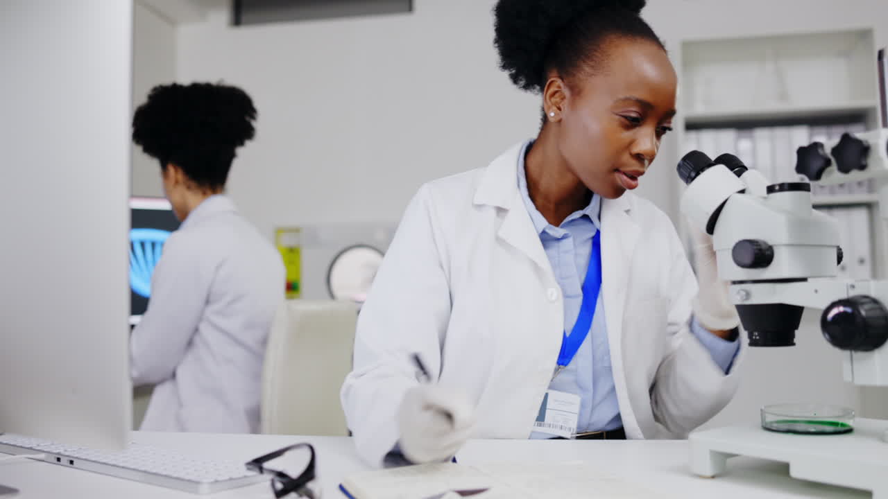Scienziata, microscopio e donna di colore che scrive