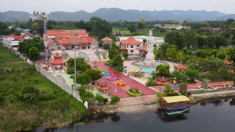 Panoramic-drone-view-of-the-Guan-Im-Sutham-Temple-situated-on-the-banks-of-the-Kwai-River,-just-beside-the-Kwai-memorial-bridge