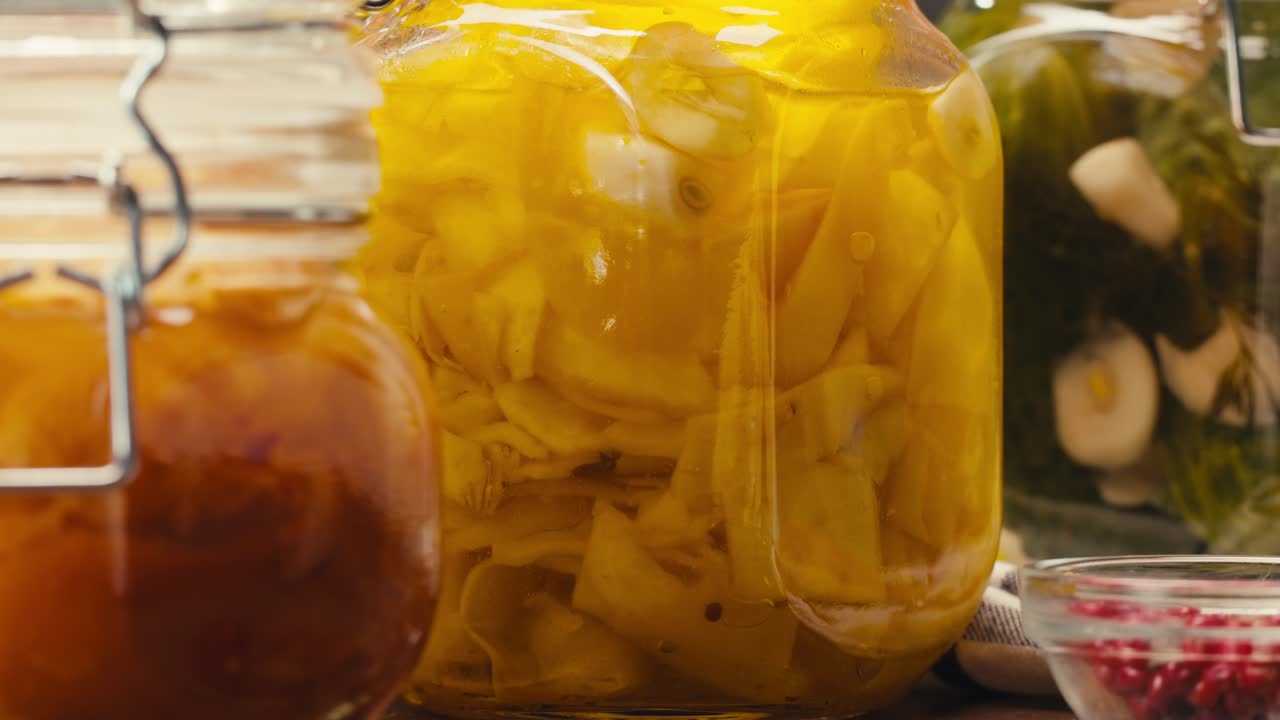Close-up of fermented yellow mini corn with black pepper in can. Preservation of vegetables in glass jars. Fermentation preserved mini corns with spices.