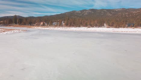 Tilting-up-shot-of-a-frozen-lake-covered-in-snow