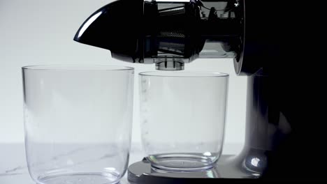 juicer with two clean glasses positioned to catch fresh juice extraction