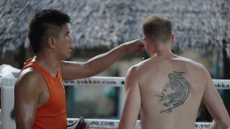 a coach pouring water on a fighter during muay thai training