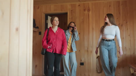 freelancer enters wooden resort room with smile, looking around with excitement and curiosity, wearing white long sleeve top and jeans, natural sunlight highlights wooden walls and relaxed setting