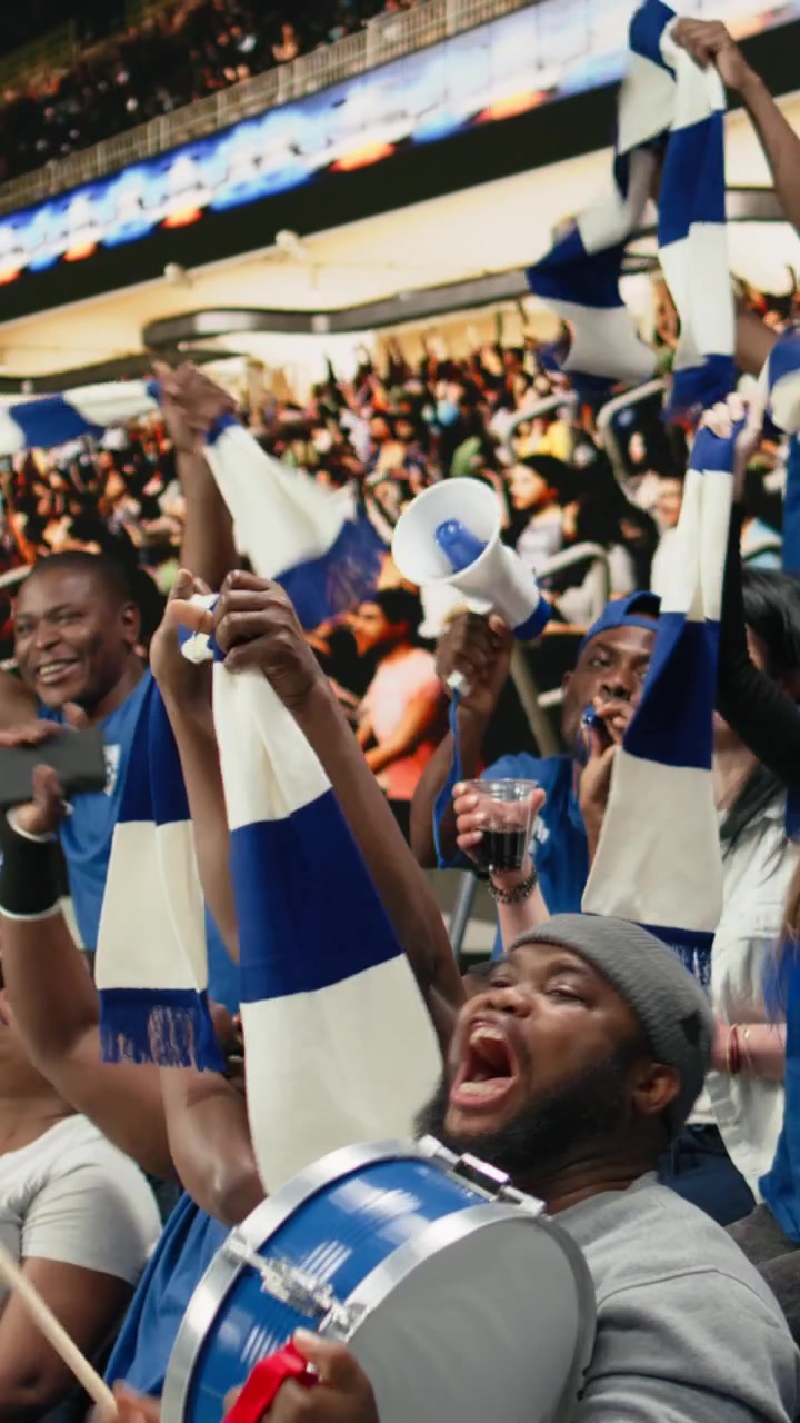 Video vertical: Líder de cánticos de fútbol soplando una vuvuzela mientras los aficionados azules responden.