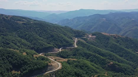 Vista-Aérea-De-La-Carretera-Rizada-En-Las-Montañas-Rhodope-Rodeada-De-árboles-Verdes