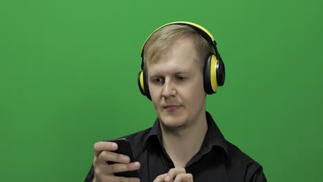 guy listens to music in wireless yellow headphones and dances. chroma key