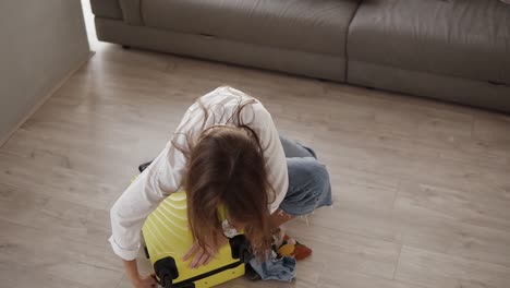 preparing bag for travel. young woman packing and desperately trying to close full suitcase, sits on it and closes a zipper being