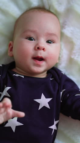 gorgeous little baby lies on the bed. cute small newborn boy. vertical video