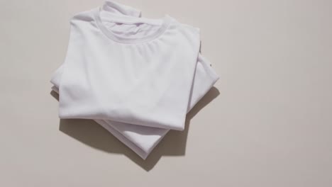 video of stack of folded white t shirts with copy space on white background