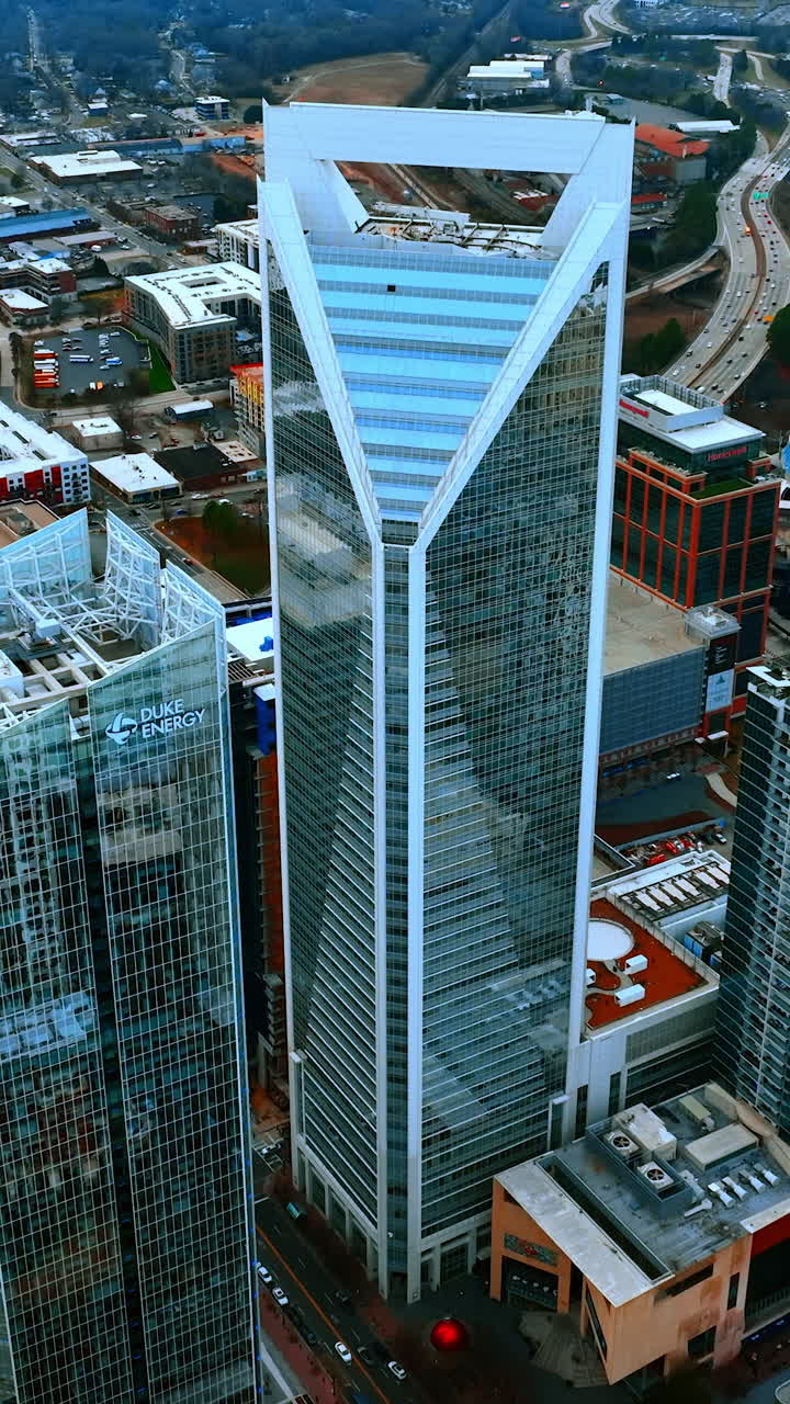 Flying around the magnificent skyscrapers with mirror windows in the downtown of Charlotte, North Carolina, USA. City scenery on cloudy daytime. Vertical video