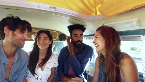 four friends on a road trip talk in the back of a camper van