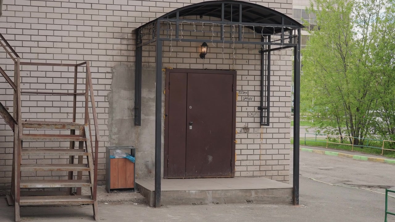 Kahverengi Metal Kapılı ve Yanıp Sönen Tente Işıklı Kentsel Bina Girişi