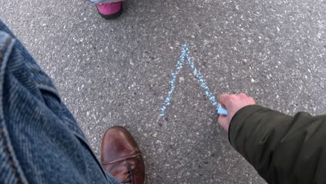 person in playground drawing letter a on asphalt ground using blue chalk. overhead shot