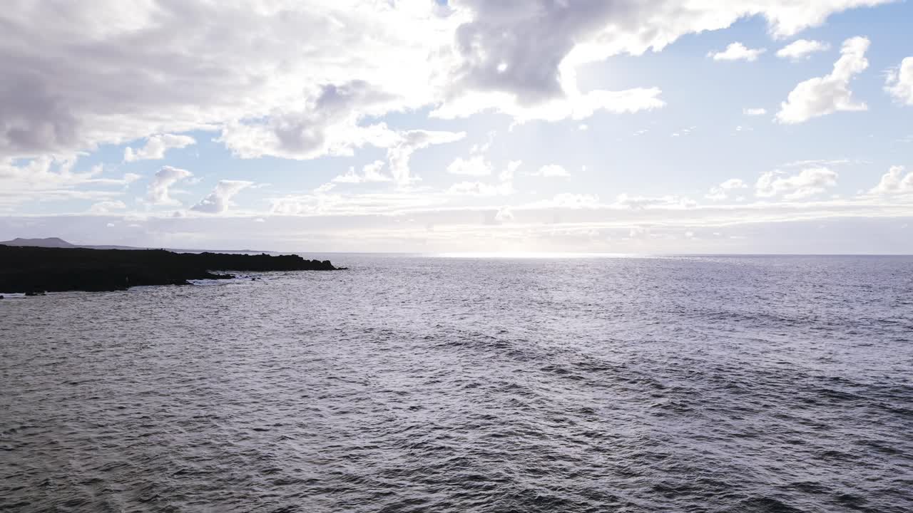 Drone che vola sopra il mare e l'aspra costa vulcanica nera al tramonto a Lanzarote, Spagna. Ripresa aerea all'indietro. Spazio per il testo.