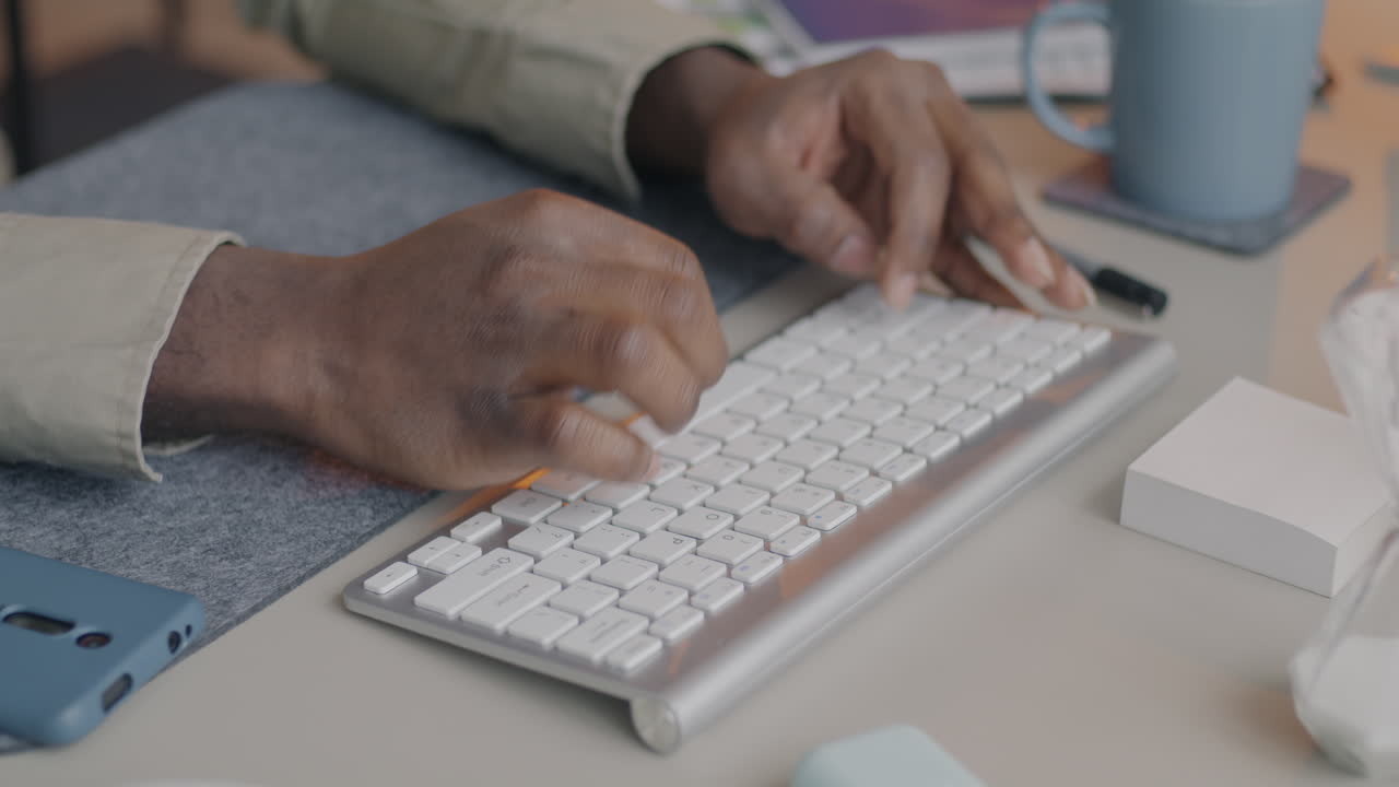 Person Typing on a Keyboard at a Desk