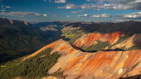 Timelapse,-Clouds-and-Shadows-Moving-Above-Stunning-Mountain-Landscape-WIth-Red-Hills-and-Green-Forest