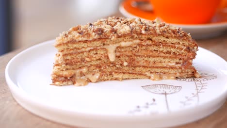 a slice of layered cake with nuts and caramel on a white plate