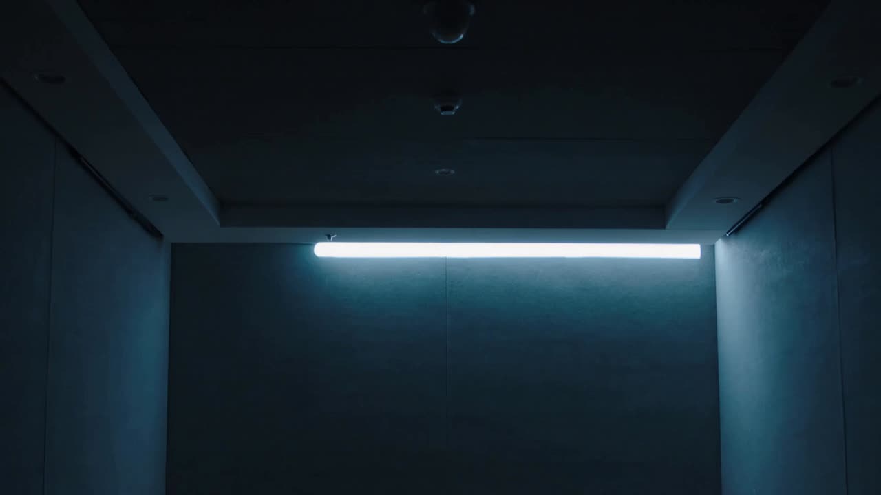 Brightening LED bar sending segmented rings down corridor wall, forming paired glowing circles