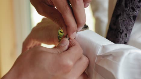 groomsman assists a groom to put on a bracelet and watch while getting ready for his wedding