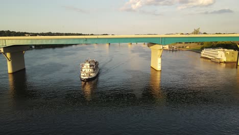 Ferry-boat-sail-under-bridge-of-Chattanooga-city,-aerial-drone-descend-view