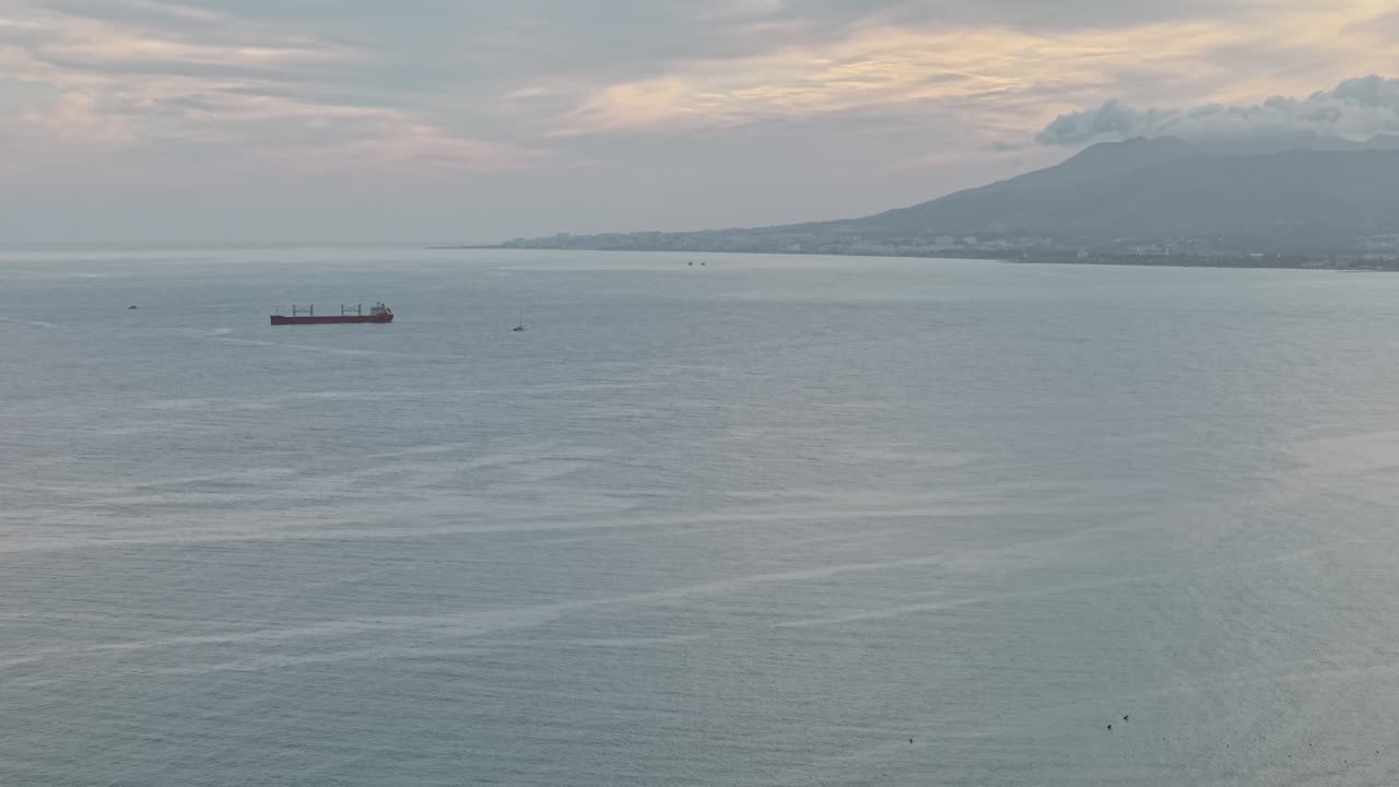 Empty cargo ship sailing alone on wide ocean in overcast weather, Málaga, Spain