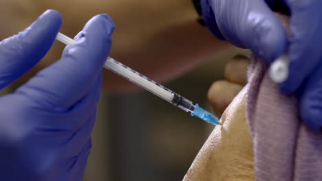 the nurse is holding a syringe making the injection to the senior citizen in the medical center