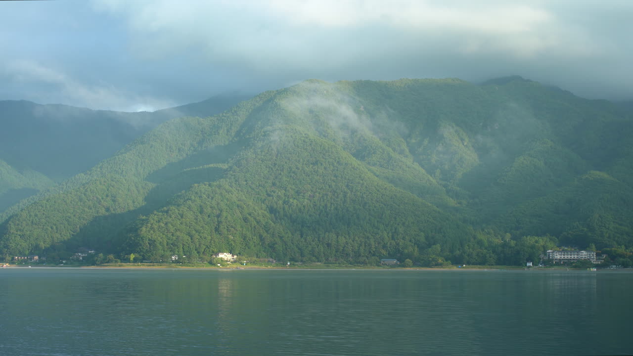 일본 혼슈에 있는 카와구치코 호수는 푸른 산과 은 구름이 평온한 물에 반사되어 호수를 정의하는 평온의 본질을 포착합니다.