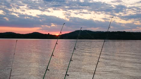 puesta de sol sobre un lago con cañas de pescar en primer plano