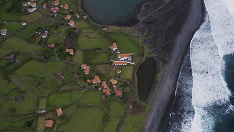 vista de arriba hacia abajo de un pueblo costero exuberante paisaje verde, fajã de santo cristo, isla de são jorge, las azores, portugal