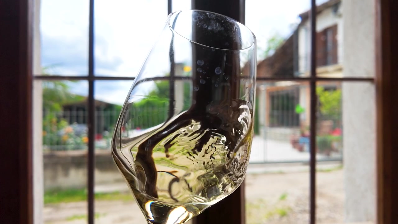 Vino bianco che volteggia in un bicchiere vicino a una finestra
