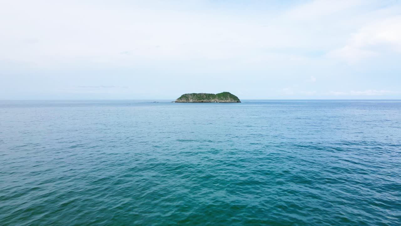 A forward-moving drone shot approaches a small tropical island off the coast of Costa Rica, revealing more detail as it gets closer