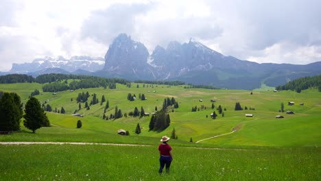 Toma-Trasera-De-Una-Mujer-Poniéndose-Un-Sombrero-Y-Contemplando-El-Seiser-Alm,-Italia.