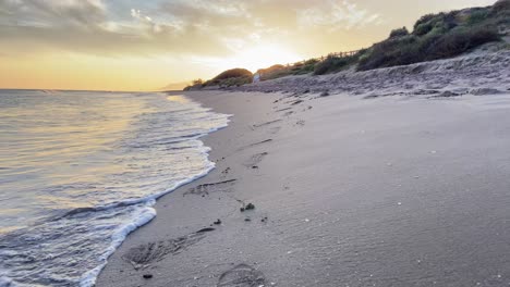 walking along the shore of a beach under a warm and magical sunset in southern spain.