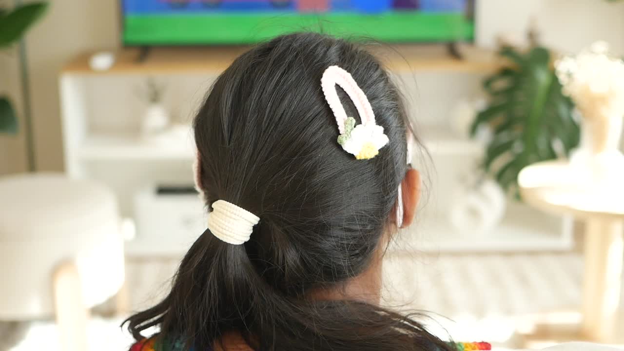 Child with hair accessories watching television