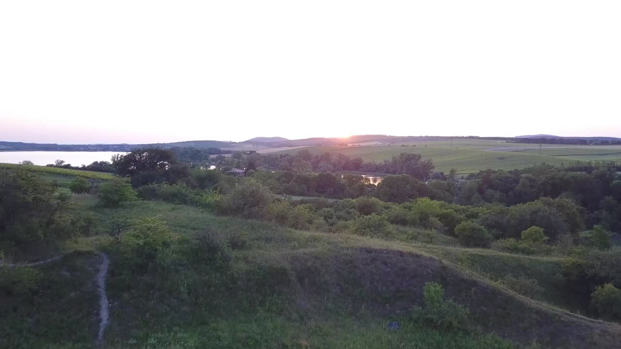 el novio y la novia de pie en las colinas durante el atardecer